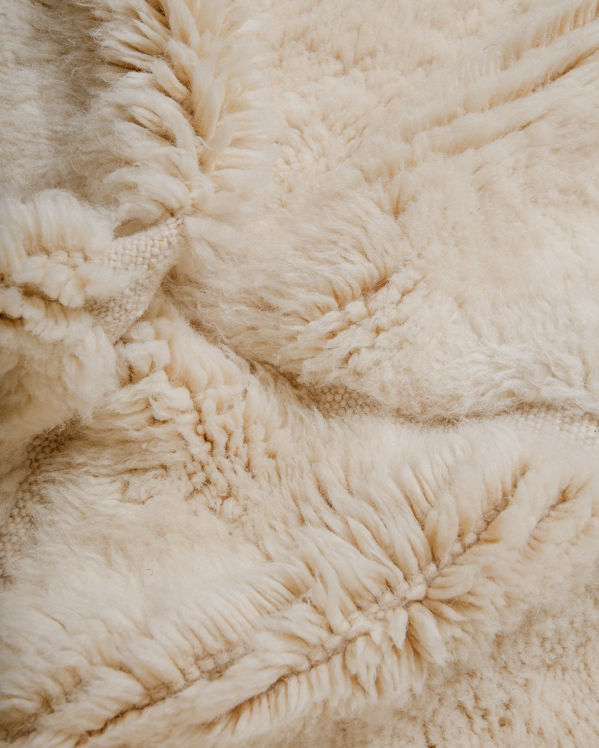 Close-up of a textured cream wool rug bunched up